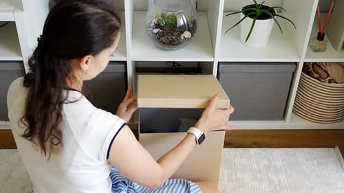 Jeune femme utilisant une boîte de rangement provenant d'un système d'étagères pour organiser l'intérieur de la maison et