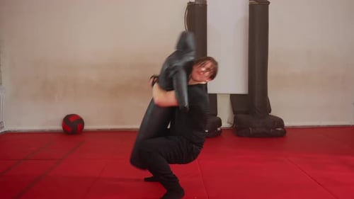 Male Fighter Practicing Grappling Techniques in Gym Training with Black Dummy