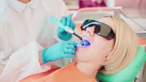 Teeth Whitening in Dentist Office Stomatologist Examining and Curing Teeth of Adult Woman Patient