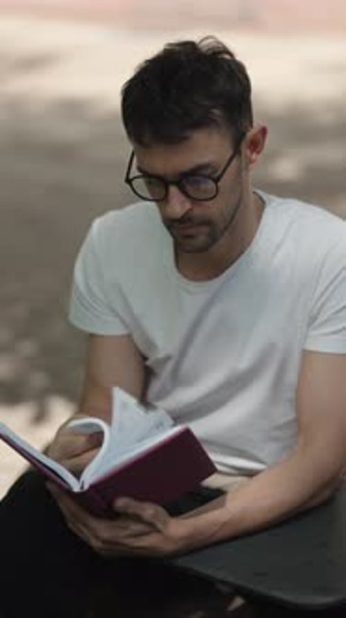 Man Reading a Book in a City Park