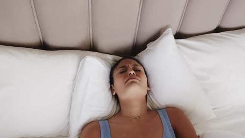 Tired woman lying in bed at home, slow motion