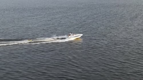 Small Boat Being Towed Behind By A Speedboat Across The Sea. tracking shot