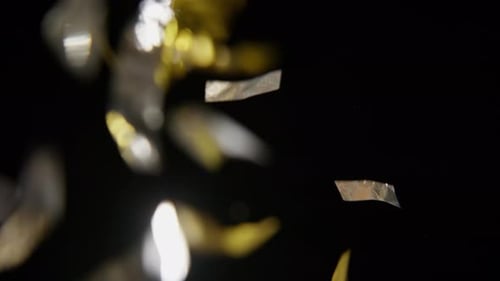 Gold and Silver Confetti Falling on Black Background
