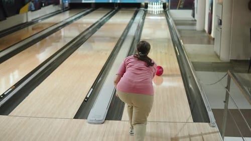 Caucasian Woman Takes Shot at Bowling Alley and Knocks Down Couple of Pins