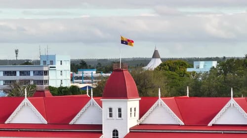 Royal Standard Flag on Kings Palace in Nukualofa, Tonga. Drone reveal building and cityscape.