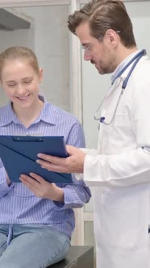 Doctor Discussing Medical Chart with Young Woman Patient