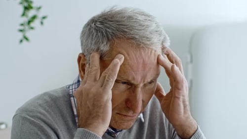 Älterer Mann, der in seinen 60ern zu Hause Beschwerden hat, während er sich entspannt