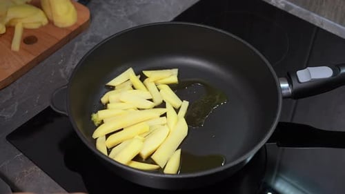 Unrecognizable Woman Placing Potato Slices on a Hot Pan Frying for Homemade Dinner