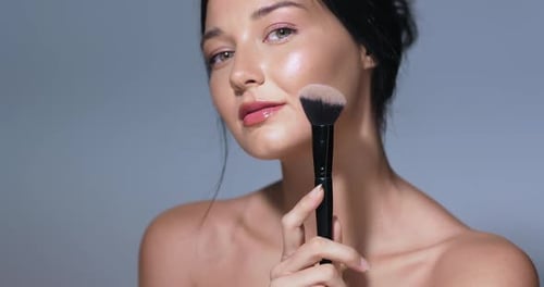 Glamorous Woman Applies Makeup with Brush