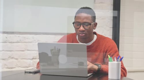 Young Adult Man Working on Laptop in Modern Office