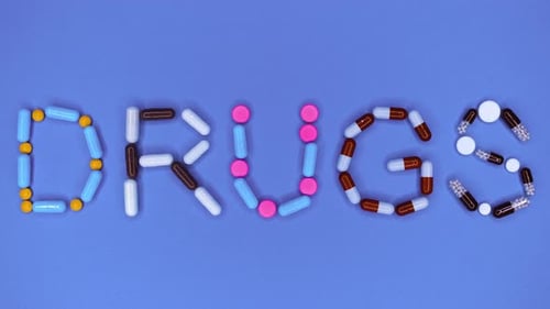 Colorful Capsules and Pills Spell the Word Drugs