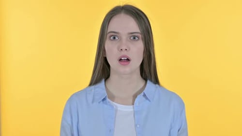 Young Woman Reacting in Surprise on Yellow Background