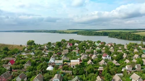 Countryside near the river in summer. Flying over village houses on nature background.