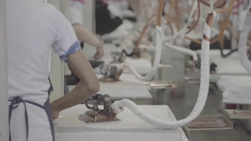 Fabrikangestellte bügeln Kleidung für die Massenproduktion in einer Bekleidungsfabrik