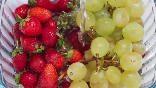Fresh Strawberries and Grapes Being Washed with Water