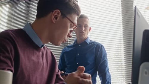 Two Male Colleagues Collaborating during Work Discussion at Office