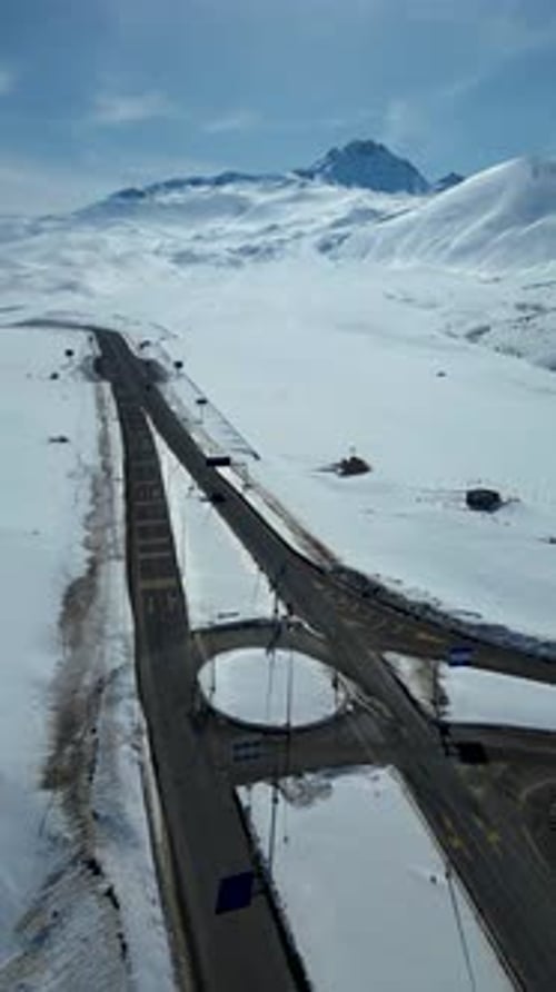 Aerial View of Winding Highway Through Snow-Covered Mountains