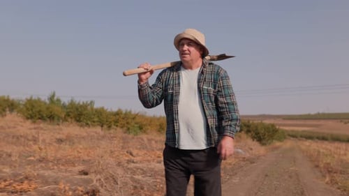 Captured in Elderly Worker with Shovel in Countryside Side View and Tracking Shot
