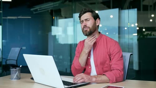 Man at Computer Experiences Sore Throat at Work