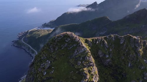Summits Reinebringen mountain range against blue sea on summer day, Reine, Norway - Aerial orbiting