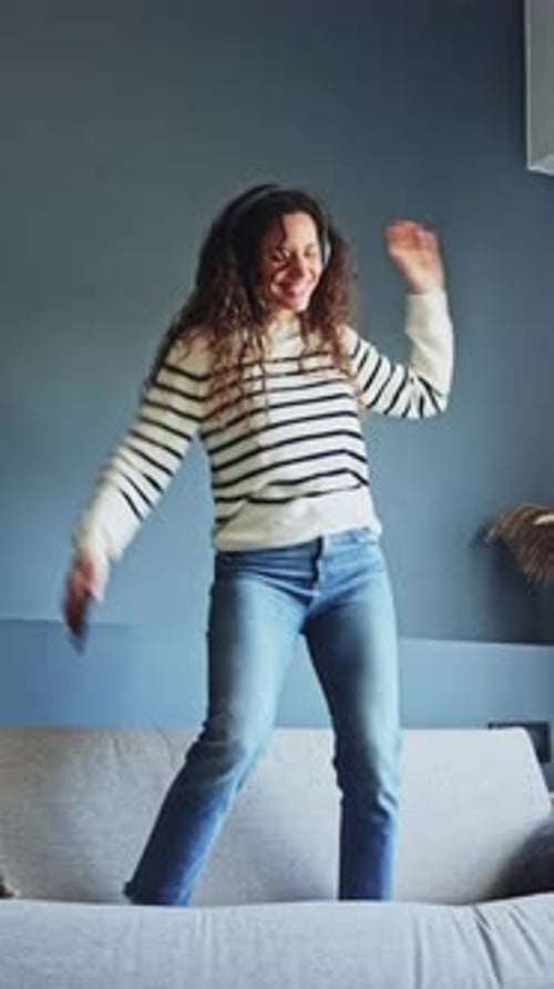 Woman Joyfully Dancing on Sofa at Home