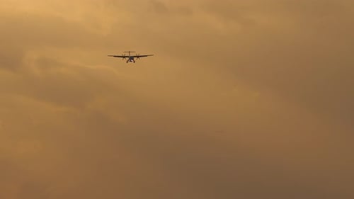 Airplane Flying During Golden Hour Against Cloudy Sky