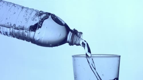 Wasserflasche, die in ein Glas gegossen wird,