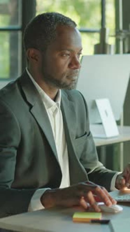 A Dedicated Professional Man Efficiently Working at His Desk Within a Modern Office Environment