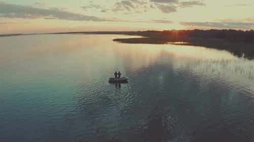 Friends fishing at sunset. Two amateur anglers fishing from the boat on a clam lake during sunset