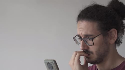 Close up with copy space of anxious man checking smartphone and biting his nails