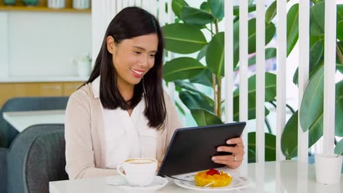Happy young asian woman enjoying coffee shop dessert with tablet technology