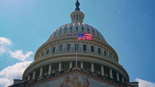 Capitol Building with American Flag Against Blue Sky