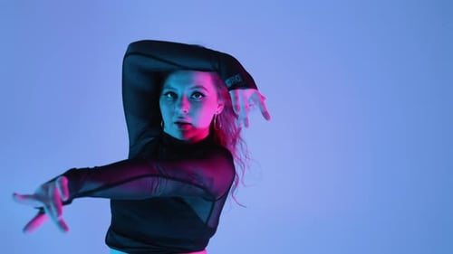 Frau tanzt mit Händen, Kopf im bunten Neonlicht, Tänzerin bewegt sich zum Musikrhythmus