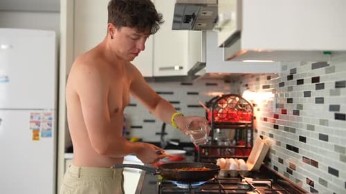 Shirtless Man Cooking Vegetables in Home Kitchen