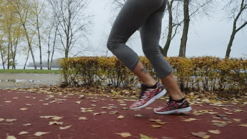 Closeup Legs of Female Runner on Park Track