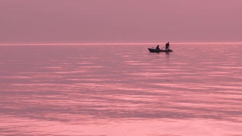 Baltic coast and purple sunset, two fishermen on boat, slow motion
