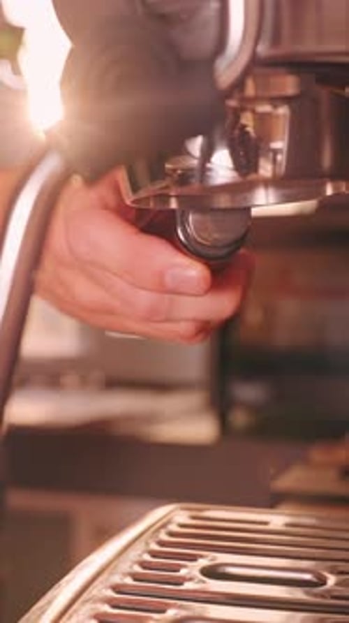 Vertical video. Man partially locking portafilter into espresso machine group head, close up first