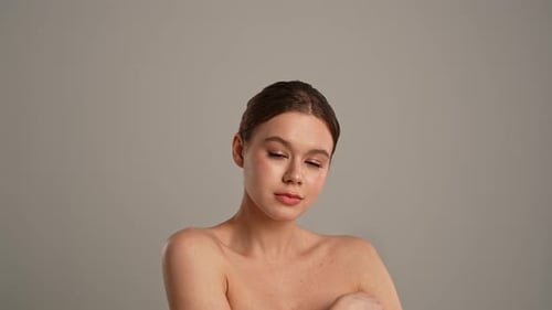 Woman with bare shoulders poses gracefully in studio