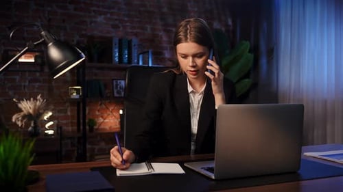 Focused Professional Writing Notes in Modern Office and Talking on Phone