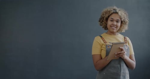 Portrait of African American Woman in Apron Waitress Taking Order Speaking and Writing in Notebook