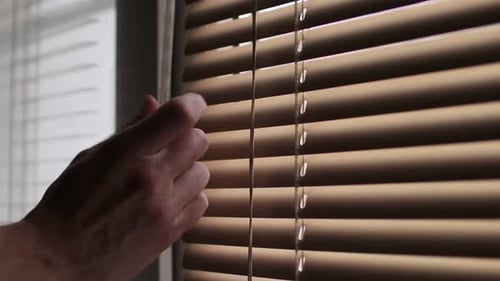 The Male Hand Rotates the Handle to Close the Horizontal Blinds Blocking the Light From the Street
