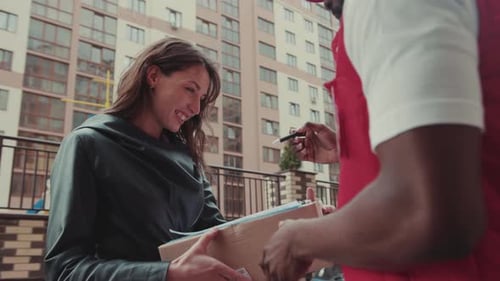Close Up Young Woman Takes the Delivery Signing Box to the Courier African American Man Cardboard