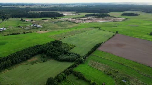 A drone view of picturesque meadows and forests located next to a small village