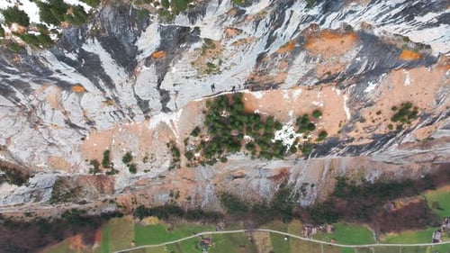 Aerial view of steep vertical mountain wall with evergreen forest on top