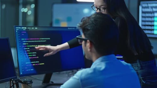 Asian woman pointing at monitor with program code