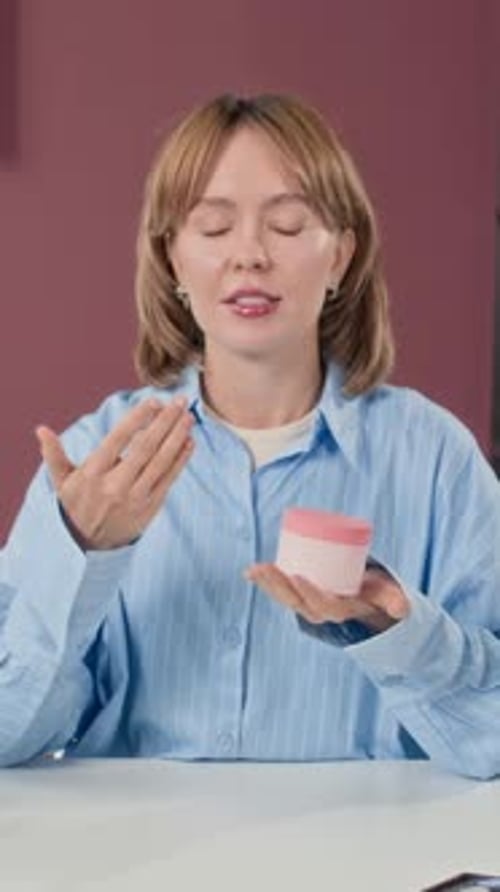 Woman Presents Beauty Cream at Desk Indoors