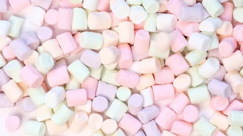 Top View of Pastel Shaped Marshmallow Candies with Some Scattered on the Pale White Table