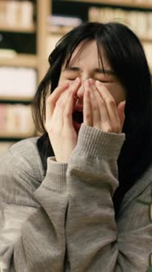 Vertical Video Fatigued Young Woman Covering Mouth Yawning Over Open Book