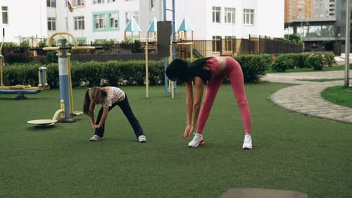Mother and Daughter Exercising Together in a Park Playground in the Morning