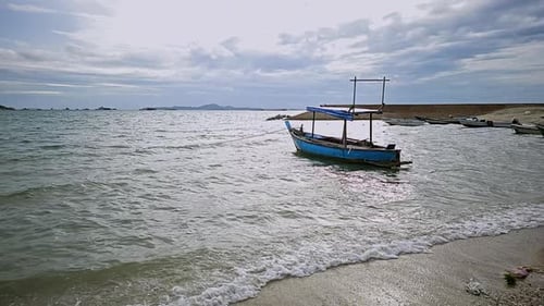 Zeitlupenaufnahme eines Strandes eines Fischerdorfs, in dem Fischerboote vor Anker liegen, in einem
